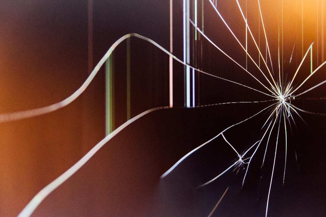 Close-up of a cracked and shattered LCD screen panel with spider-web fracture lines