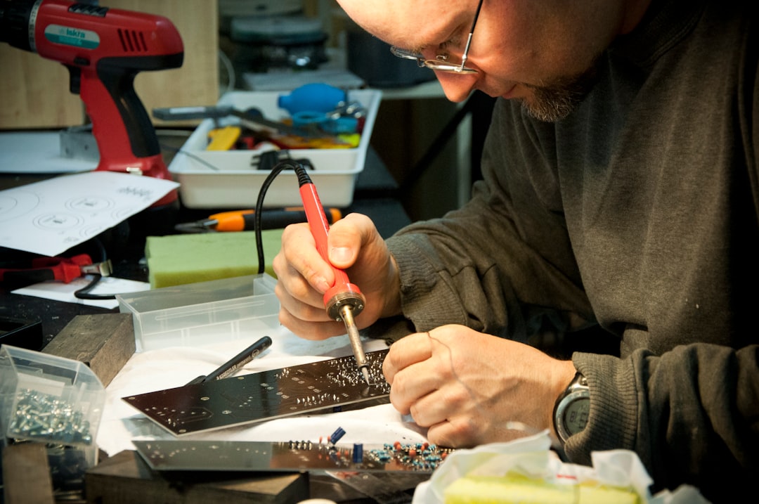 Electronics technician repairing a circuit board in a workshop – TV repair service Abu Dhabi