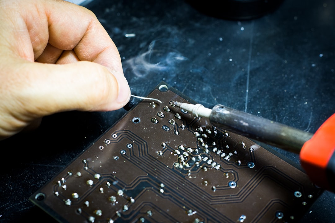 Close-up of electronics repair technician soldering a circuit board for TV repair in Abu Dhabi