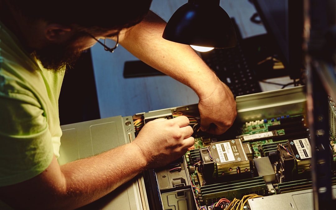 Technician repairing electronics under a workshop lamp, inspecting internal components
