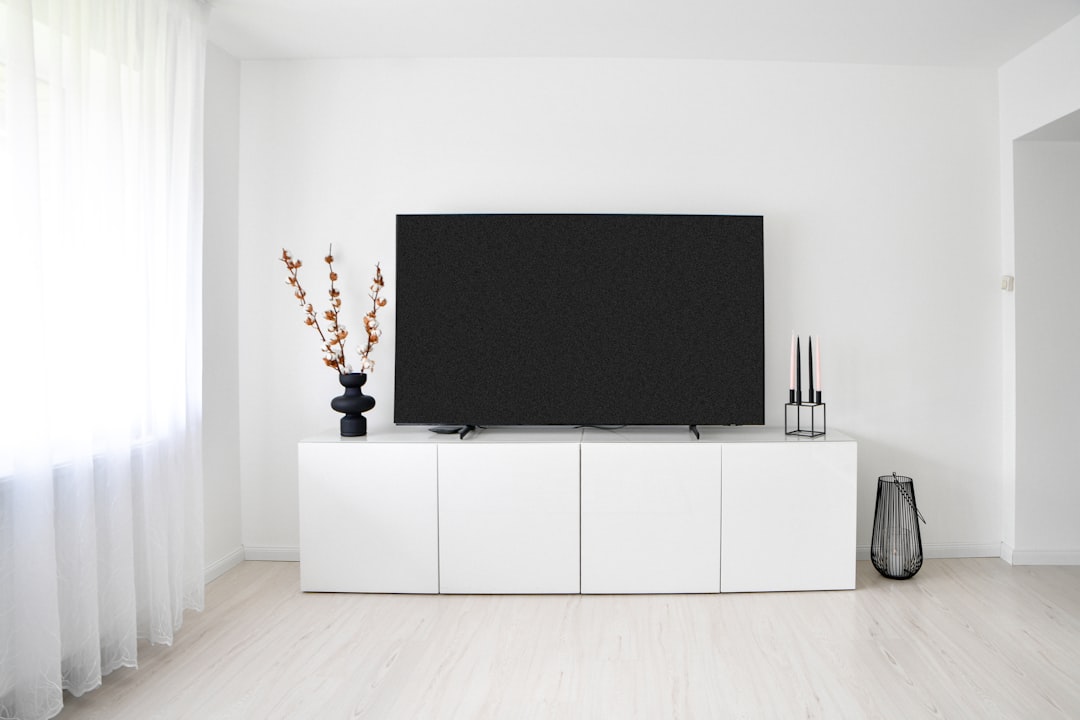 Modern flat screen LED TV on white console in minimalist living room – TV repair Abu Dhabi